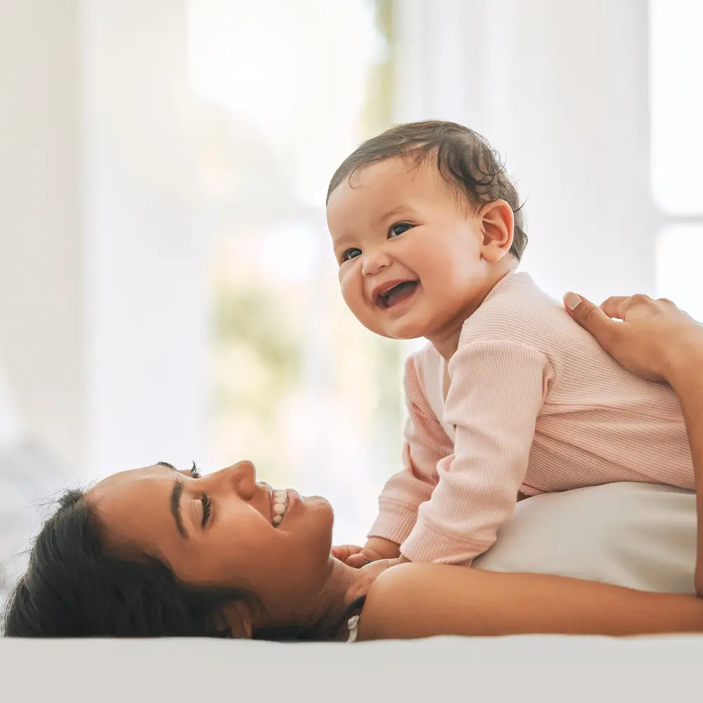 mother with happy baby laying on her stomache pushing up with hands and arms to represent crawling delay